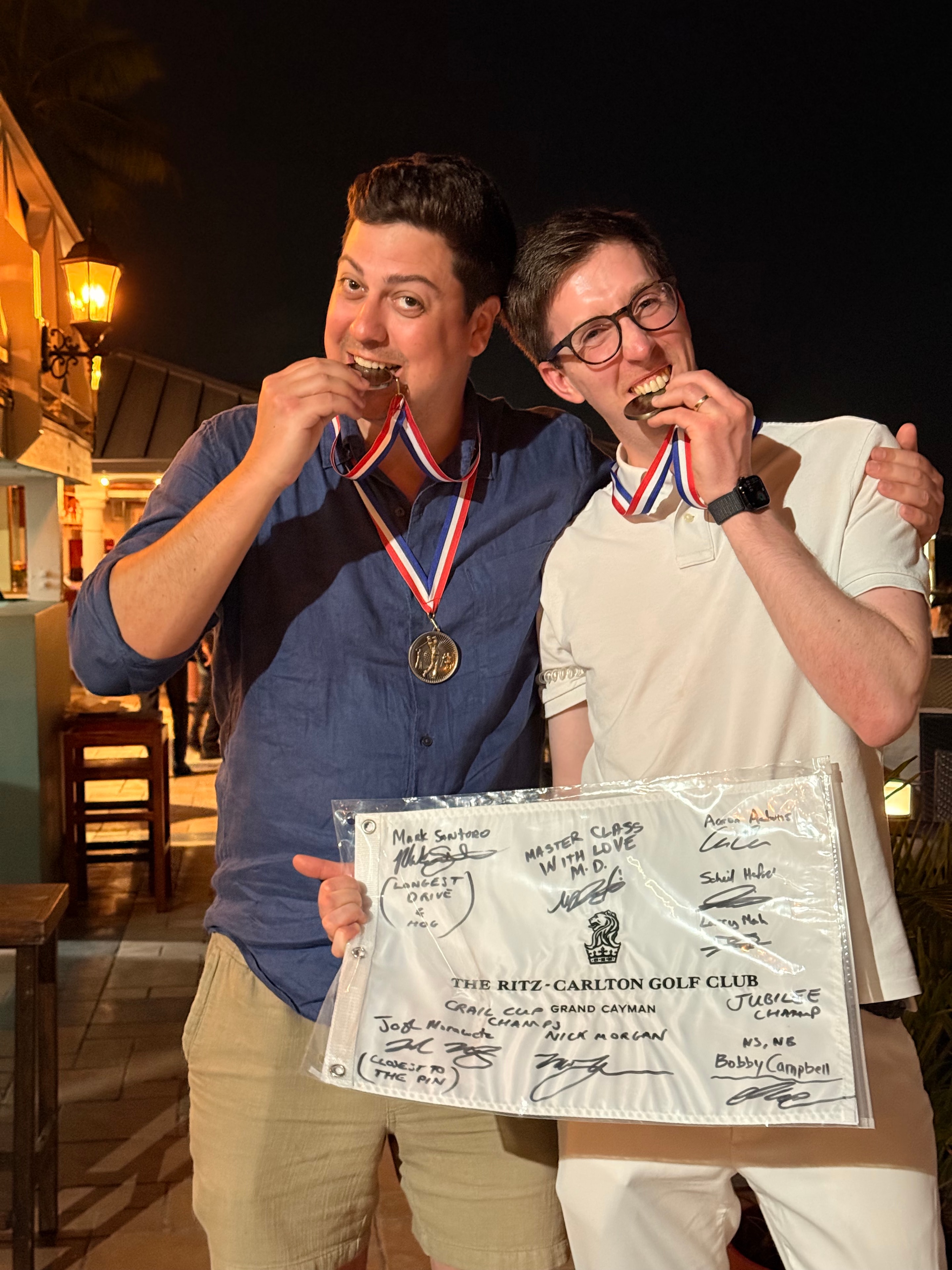 Champions displaying medals and the signed Ritz-Carlton pin flag
